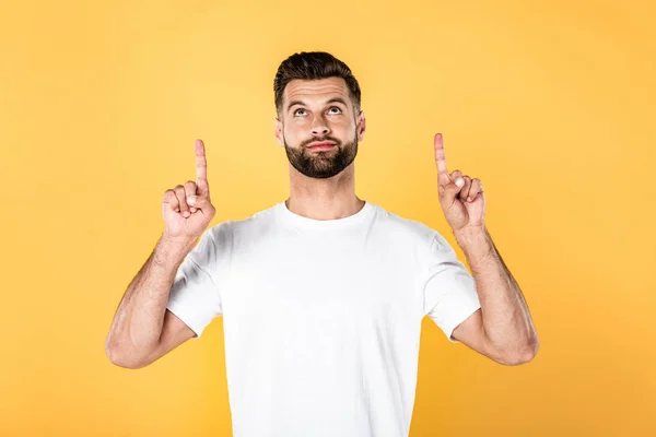 Bellissimo uomo in t-shirt bianca che punta con le dita sopra isolate sul giallo — Foto stock