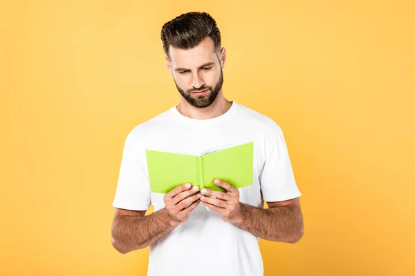 Homme en t-shirt blanc livre de lecture isolé sur jaune — Photo de stock