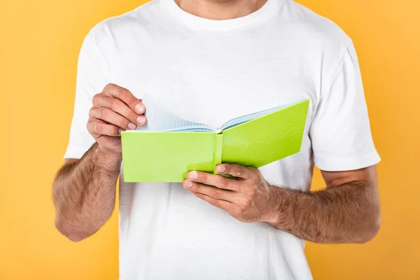 Vista cortada do homem em livro de leitura de t-shirt branco isolado em amarelo — Fotografia de Stock