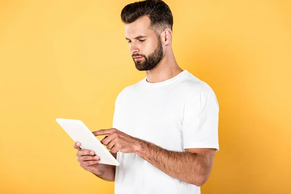 Bel homme en t-shirt blanc utilisant une tablette numérique isolée sur jaune — Photo de stock