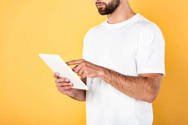 Vista recortada del hombre en camiseta blanca usando tableta digital aislada en amarillo - foto de stock