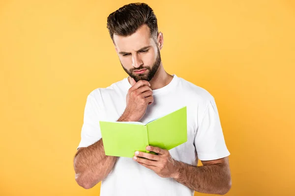 Homem pensativo leitura livro isolado no amarelo — Fotografia de Stock