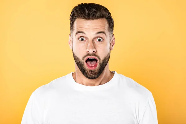 Homme beau choqué en t-shirt blanc avec bouche ouverte isolé sur jaune — Photo de stock