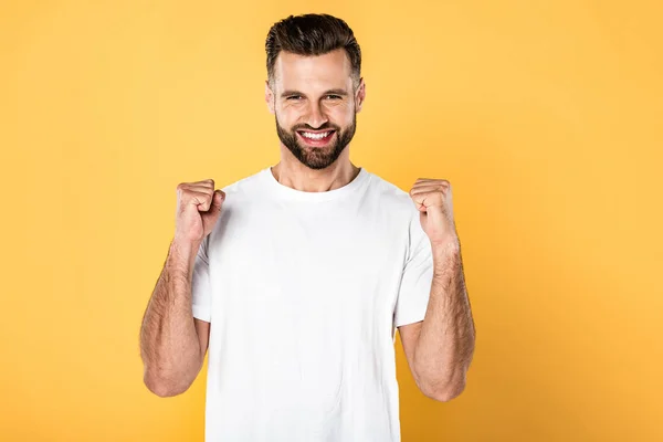 Hombre excitado en camiseta blanca mostrando sí gesto aislado en amarillo - foto de stock
