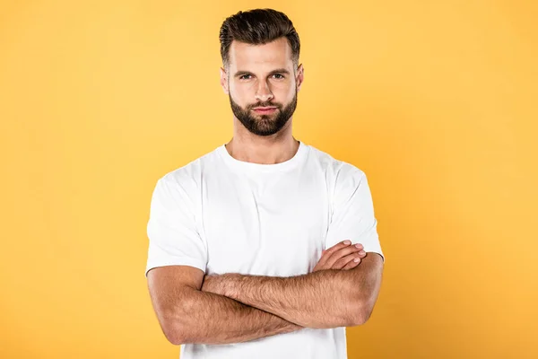 Homem bonito em t-shirt branca com braços cruzados isolados em amarelo — Fotografia de Stock