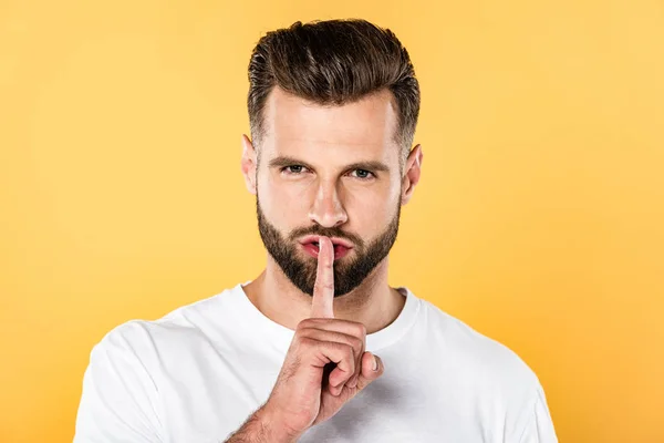 Hombre guapo en camiseta blanca que muestra un signo de silencio aislado en amarillo - foto de stock