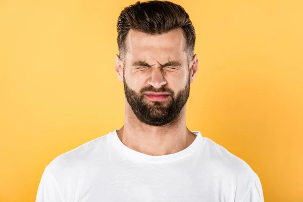 Scared handsome man in white t-shirt squinting isolated on yellow — Stock Photo