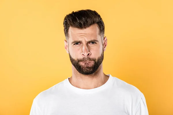 Verwirrter gutaussehender Mann in weißem T-Shirt grimmig vereinzelt auf gelb — Stockfoto