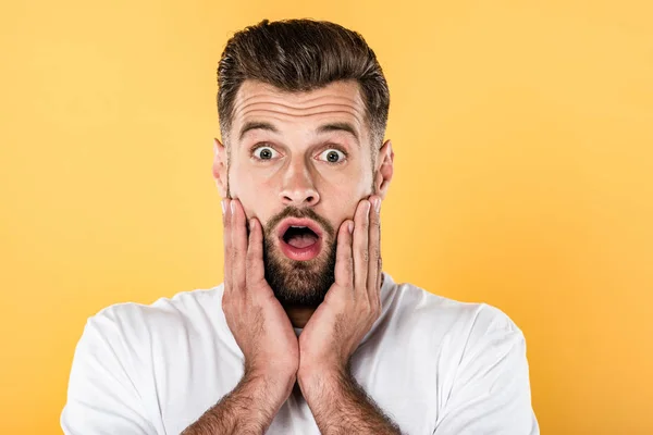Scared handsome man in white t-shirt with open mouth isolated on yellow — Stock Photo