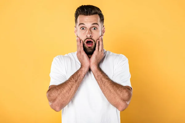 Frightened handsome man in white t-shirt isolated on yellow — Stock Photo