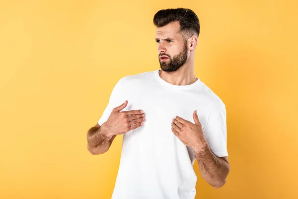 Indignant handsome man in white t-shirt isolated on yellow — Stock Photo