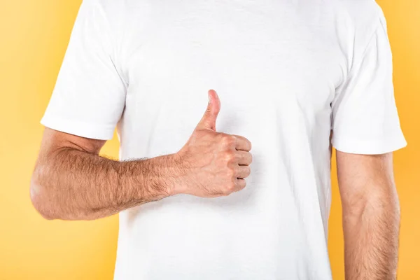 Vista recortada del hombre en camiseta blanca que muestra el pulgar hacia arriba aislado en amarillo - foto de stock