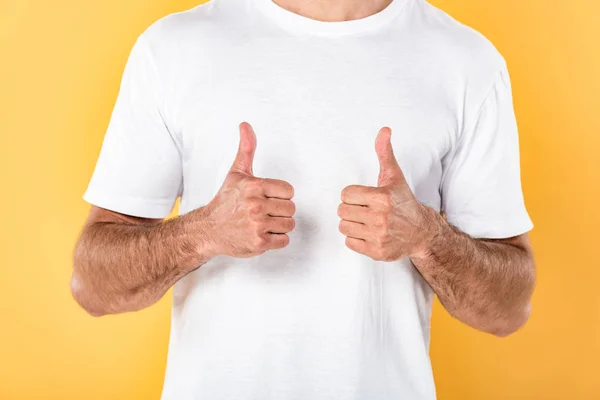 Partial view of man in white t-shirt showing thumbs up isolated on yellow — Stock Photo