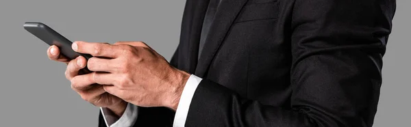 Teilaufnahme des Geschäftsmannes im schwarzen Anzug mit Smartphone isoliert auf grauem, panoramischem Bild — Stockfoto