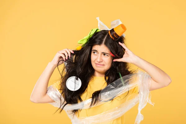 Frustrated woman with trash in hair isolated on yellow — Stock Photo