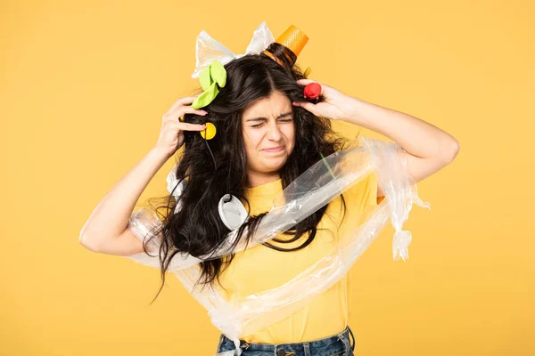 Émotionnelle jeune femme avec des déchets dans les cheveux isolés sur jaune — Photo de stock