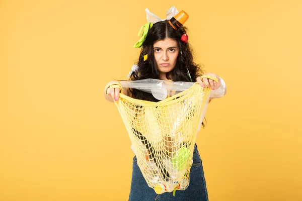 Fille confus avec poubelle dans le sac de maintien des cheveux avec des déchets isolés sur jaune — Photo de stock