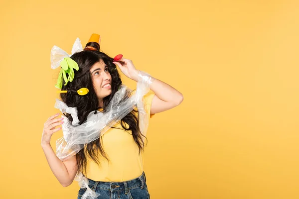 Frustrated beautiful woman with rubbish in hair isolated on yellow — Stock Photo