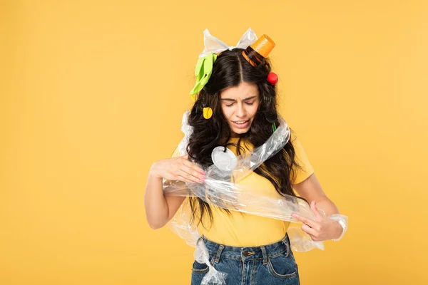 Confused young woman with rubbish in hair isolated on yellow — Stock Photo