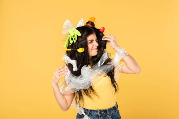 Frustrata giovane donna con spazzatura in capelli isolati su giallo — Foto stock