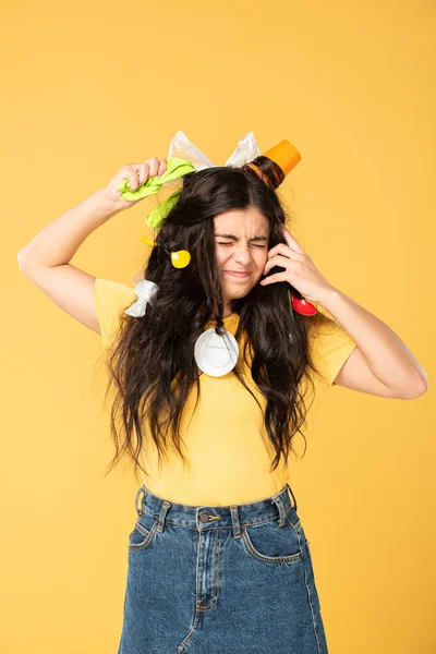 Worried girl with rubbish in hair isolated on yellow — Stock Photo