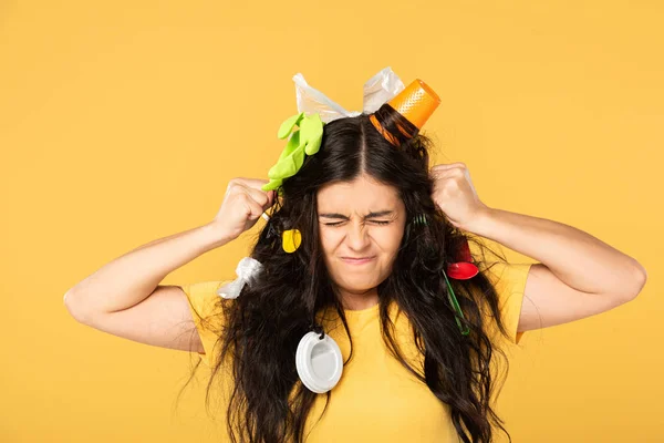Эмоциональная молодая женщина с мусором в волосах изолированы на желтый — стоковое фото