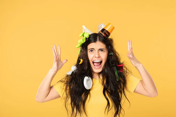 Shocked brunette girl screaming with rubbish in hair isolated on yellow — Stock Photo