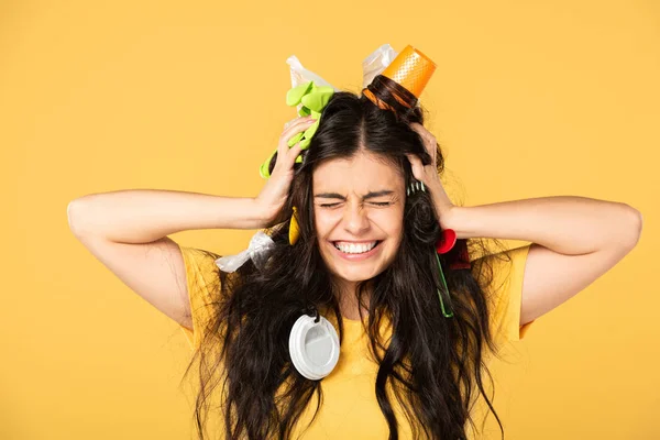 Shocked young woman with rubbish in hair isolated on yellow — Stock Photo