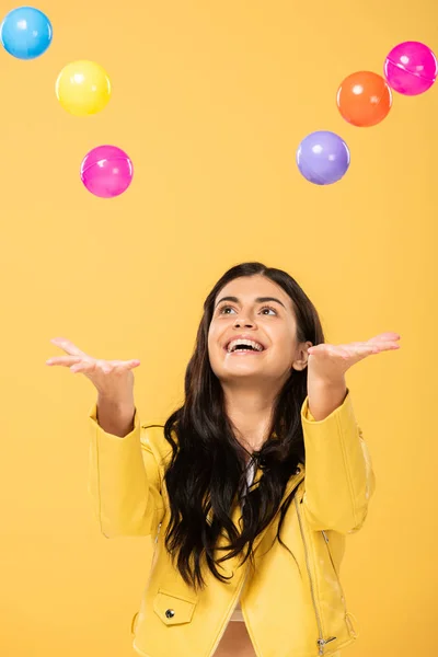 Schöne aufgeregte Mädchen mit bunten Kugeln, isoliert auf gelb — Stockfoto