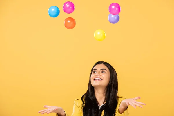 Взволнованная девушка с цветными шариками, изолированными на желтом — стоковое фото