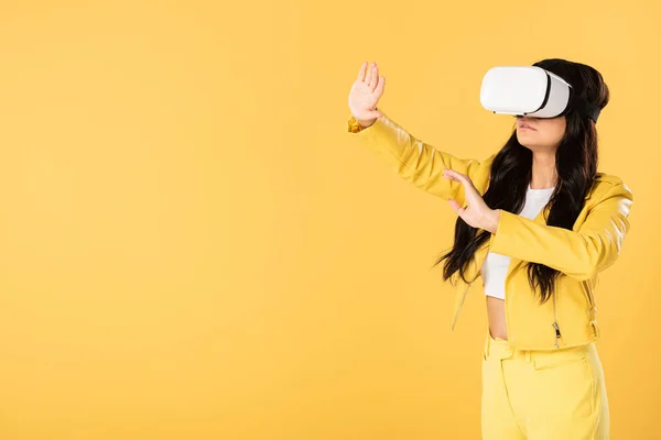 Красива емоційна дівчина з використанням гарнітури віртуальної реальності, ізольована на жовтому — стокове фото