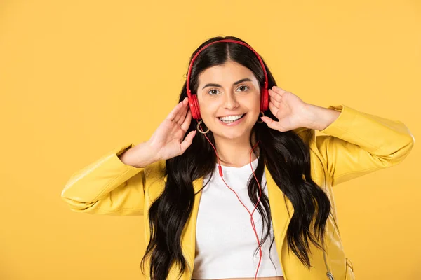 Allegra ragazza ascoltare musica con le cuffie, isolato su giallo — Foto stock