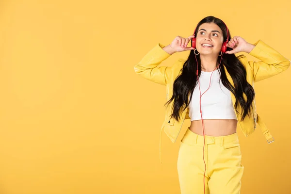 Happy young woman listening music with headphones, isolated on yellow — Stock Photo
