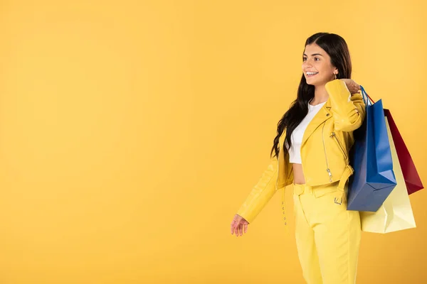 Bela mulher com sacos de compras, isolado em amarelo — Fotografia de Stock