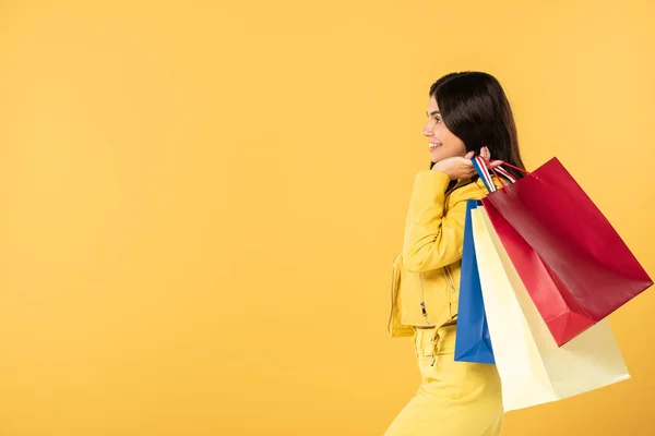 Menina feliz com sacos de compras, isolado em amarelo — Fotografia de Stock