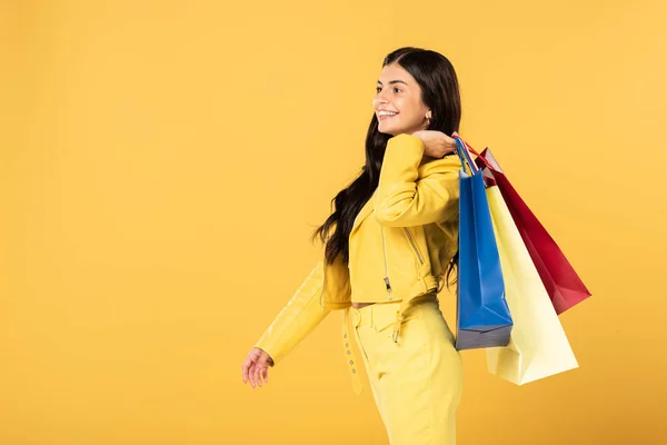 Bela jovem com sacos de compras, isolado em amarelo — Fotografia de Stock