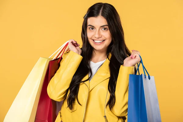 Gaie belle femme tenant des sacs à provisions, isolé sur jaune — Photo de stock