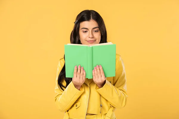 Attractive cheerful girl reading book, isolated on yellow — Stock Photo