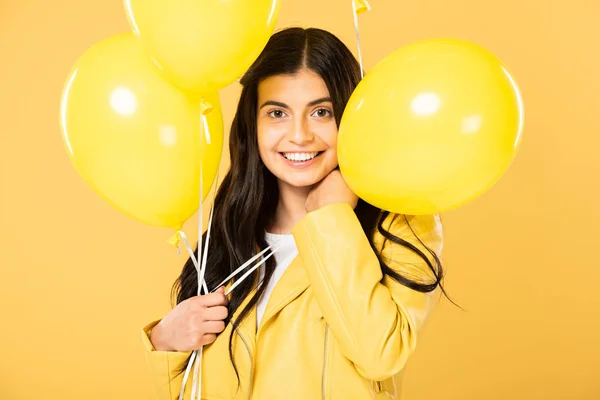 Beautiful smiling woman holding yellow balloons, isolated on yellow — Stock Photo