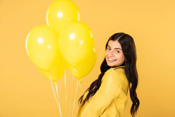 Bruna donna felice con palloncini gialli, isolata sul giallo — Foto stock