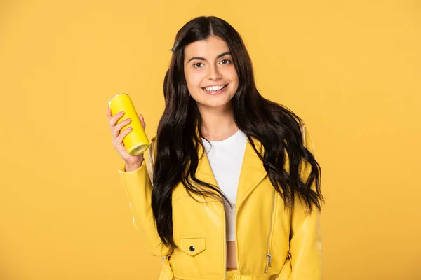 Bela menina sorridente segurando lata de refrigerante, isolado no amarelo — Fotografia de Stock