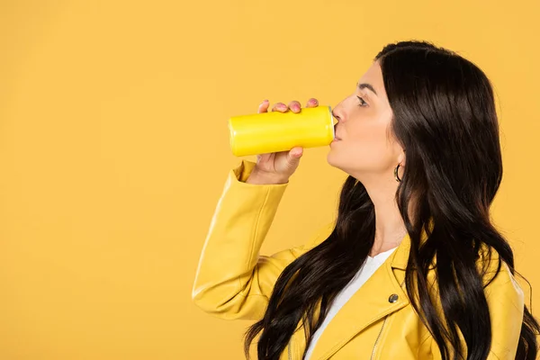 Attractive girl drinking soda from can, isolated on yellow — Stock Photo