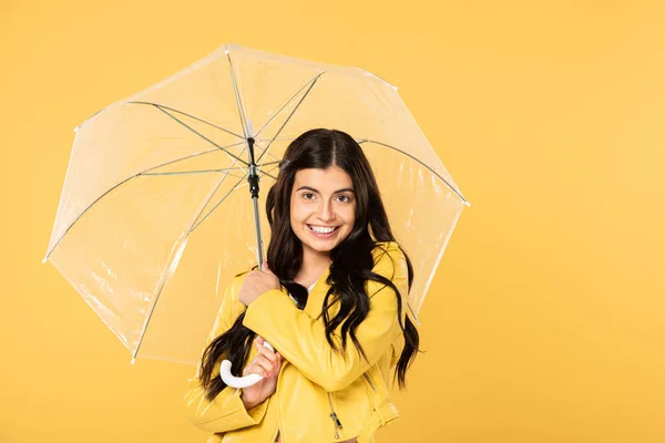 Belle fille souriante posant avec parapluie transparent, isolé sur jaune — Photo de stock