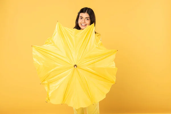 Niña sonriente posando con paraguas, aislada en amarillo - foto de stock