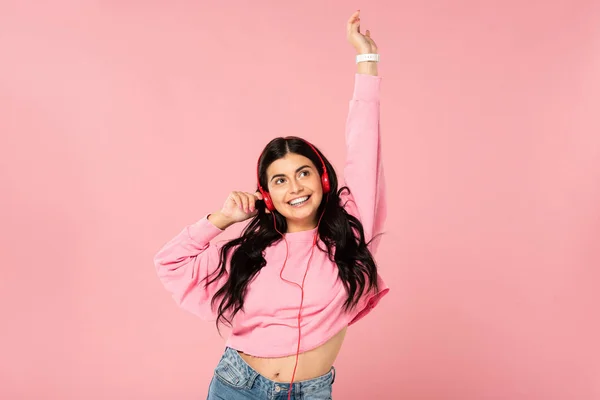 Hermosa chica feliz escuchando música con auriculares, aislado en rosa - foto de stock