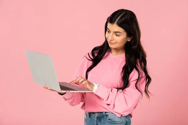 Bella ragazza utilizzando il computer portatile, isolato su rosa — Foto stock