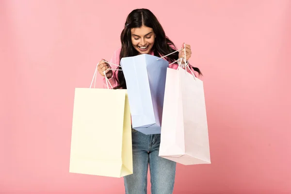 Menina sorridente atraente segurando sacos de compras, isolado em rosa — Fotografia de Stock