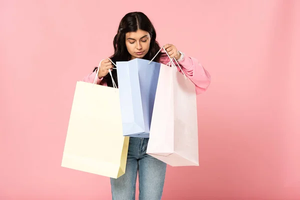 Belle fille regardant dans des sacs à provisions, isolé sur rose — Photo de stock