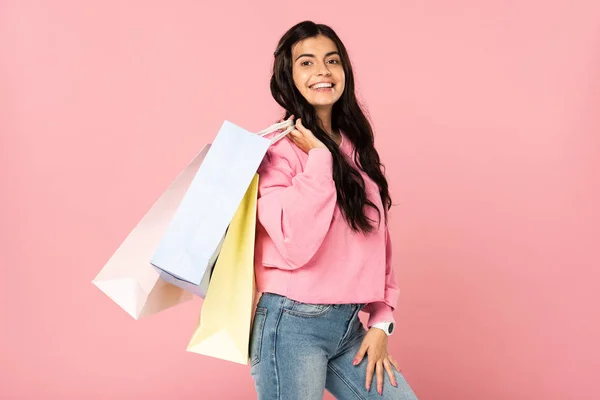 Hermosa mujer sosteniendo bolsas de compras, aislado en rosa - foto de stock