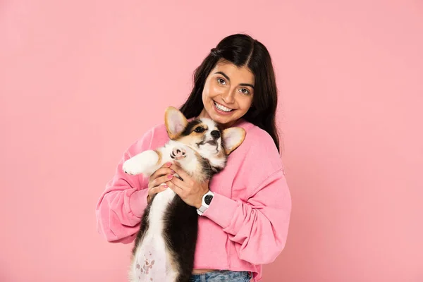 Lächelndes Mädchen mit weißem Corgi-Welpen, isoliert auf rosa — Stockfoto